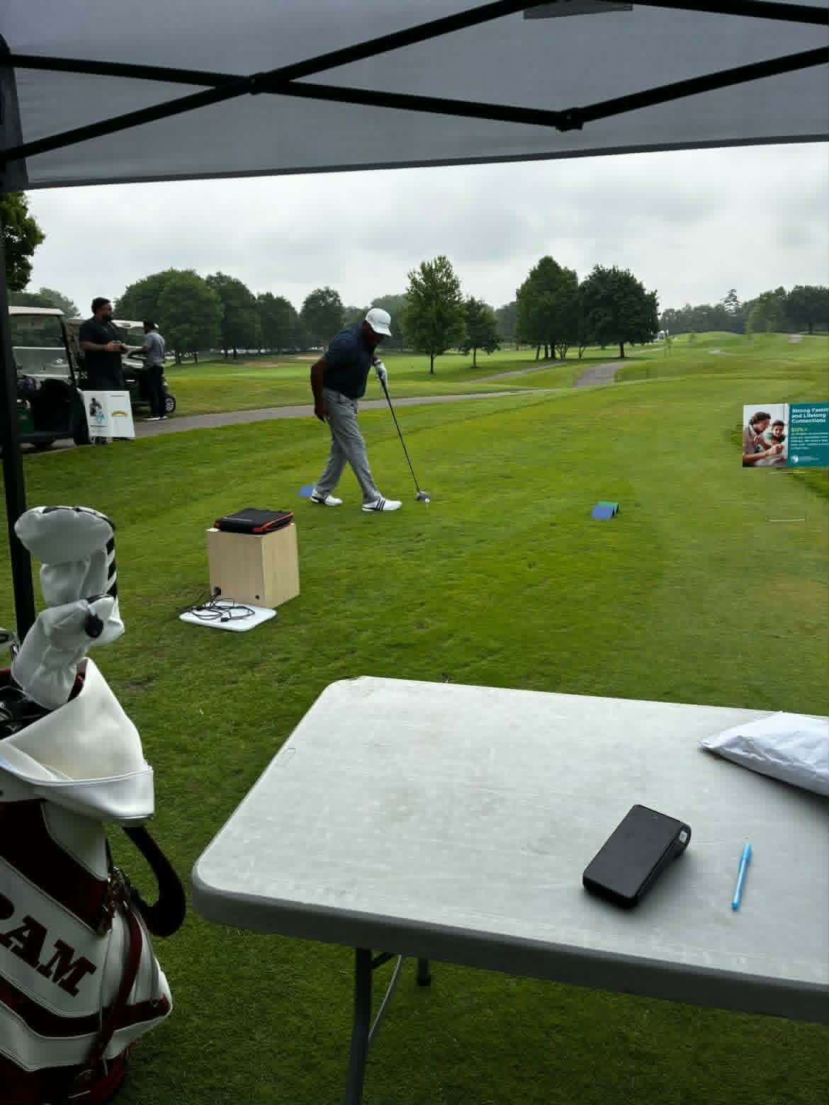 TrackMan long drive hole setup under a tent on a golf course tee box