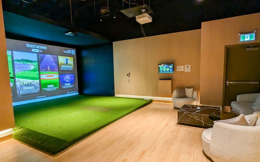 Commercial golf simulator bay with wide projection screen